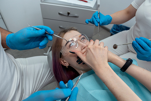 Fear of dentist or fear of the doctor of a young female patient who covers her mouth with her hands. Scared and nervous patient in the hospital.