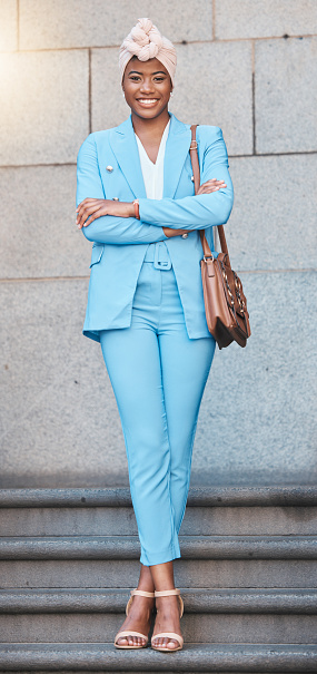 Crossed arms, smile and portrait of businesswoman on stairs in the city by her office building. Happy, briefcase and full body of professional African female lawyer with confidence in an urban town.