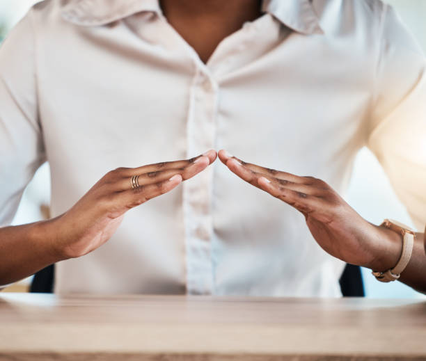 Hand gesture, insurance and a black woman broker at a desk in her office for home loan, mortgage or cover. Hands, security and safety with a female agent sitting in the workplace for a surety offer gesto con la mano, seguro y una corredora negra en un escritorio de su oficina para un préstamo hipotecario, una hipoteca o una cobertura. manos, seguridad y protección con una agente femenina sentada en el lugar de trabajo para una oferta de garantía