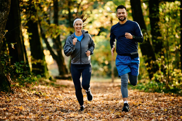 istock Happy athletic couple jogging through nature during autumn day 1796859329