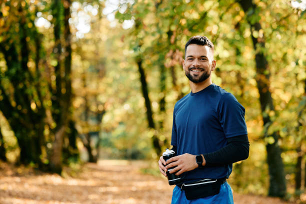 istock Happy athletic man with water bottle in the park looking at camera. 1796859897
