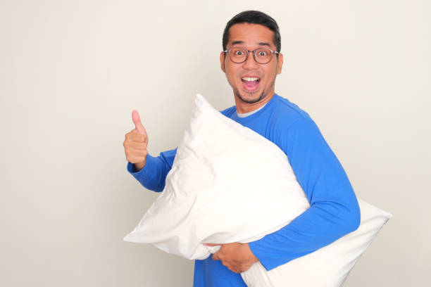 istock Side view of a man holding a pillow with excited expression and give thumb up 1796860459