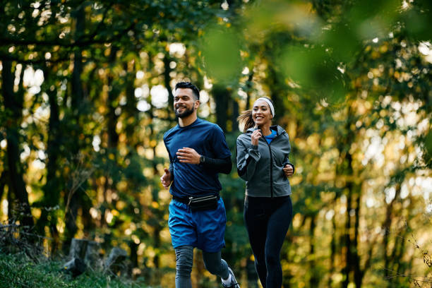 istock Young happy athletic couple running while exercising in nature. 1796864329