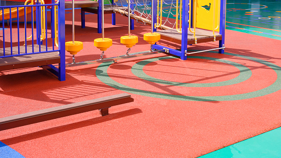 Playground climbing equipment with balance beams on colorful rubber floor in outdoors playground area at kindergarten school
