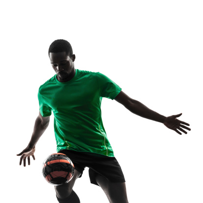 one african man soccer player green jersey juggling in silhouette isolated on white background