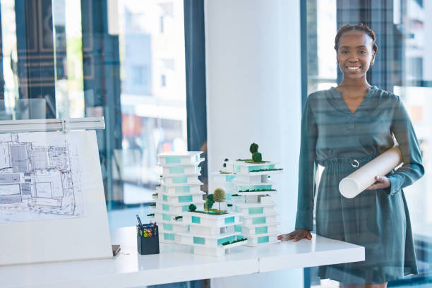 istock Leader, ambitious and successful female architect hold blueprint plans and standing with building model in a startup company. A professional engineer or structure designer holding architecture design 1796900871