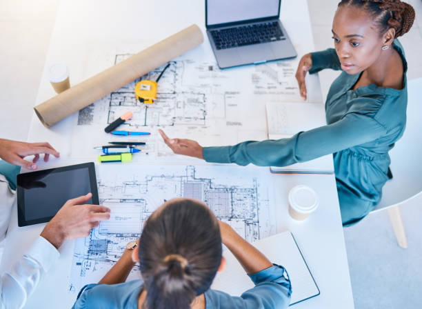 istock Architects and business woman discuss building project plan, taking notes on laptop and digital tablet. Professional construction and engineering design firm planning real estate pricing negotiation. 1796900874