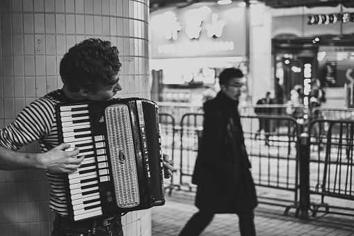 hong kong, China – February 27, 2014: A black and white shot of a young man playing the accordion on the streets of Hong Kong.