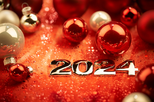 Still Life photography of the shiny number 2024 surrounded Christmas ornaments. Native image size: 7952x5304