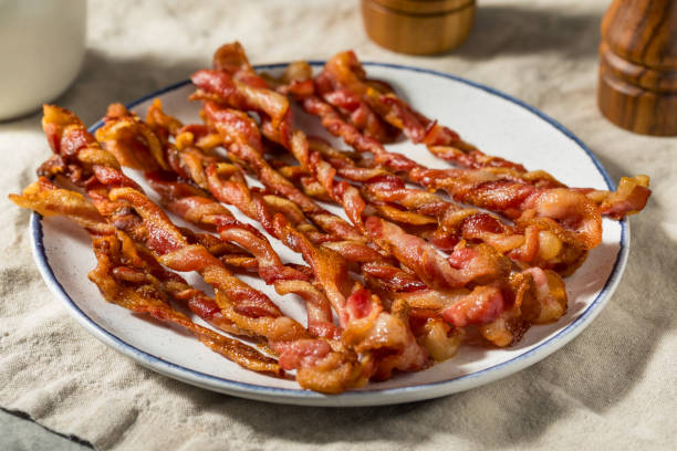 Homemade Trendy Twisted Bacon Strips Homemade Trendy Twisted Bacon Strips on a Plate twisted bacon stock pictures, royalty-free photos & images