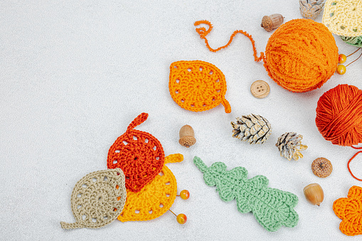 Set of clew of thread for knitting. Crocheted different leaves, handmade, autumn hobby concept. Props and special craft tools on light stone concrete background, top view