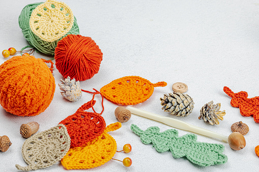 Set of clew of thread for knitting. Crocheted different leaves, handmade, autumn hobby concept. Props and special craft tools on light stone concrete background, top view