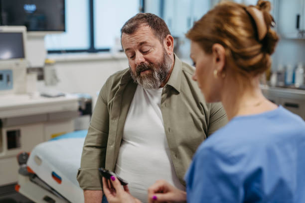 Doctor checking blood glucose level using a fingerstick glucose meter, waiting for results from glucometer. Obese, overweight man is at risk of developing type 2 diabetes. Concept of health risks of overwight and obesity.