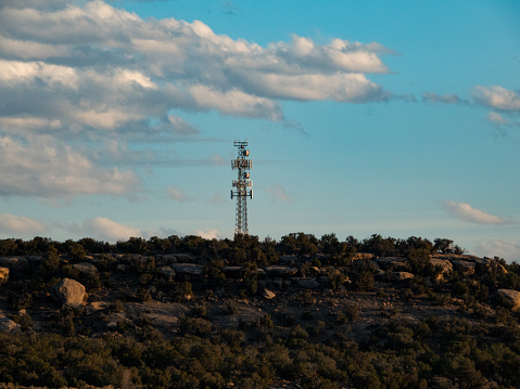 Distant cell and microwave tower among the rock and junipers in the Utah desert.