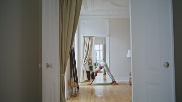 Yoga model training domestic interior. African girl doing flexibility exercises