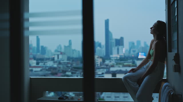 Woman sitting on the balcony with view of big city and relaxing