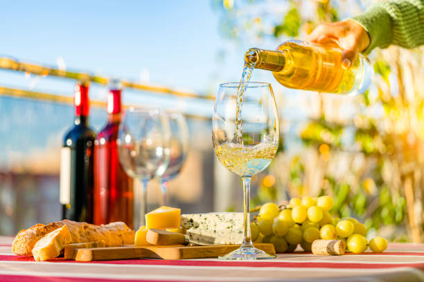 mano de la mujer que vierte vino blanco de la botella en un vaso al aire libre - gewurztraminer fotografías e imágenes de stock