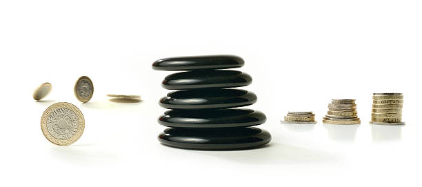 Financial Balance 4 A concept image relating to financial matters. Spinning coins representing investments, pension or savings with Feng Shui black stones representing balance and the final calm result. White background with copy space. golden nest egg taxes stock pictures, royalty-free photos & images