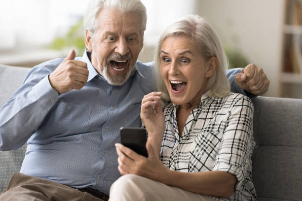 istock Excited surprised retired couple holding mobile phone 1796991386
