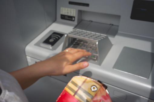 Close up of human hands safety entering ATM cash machine PIN code.