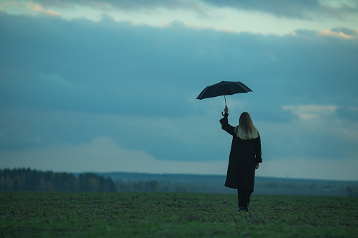 Woman with umbrella on the field.