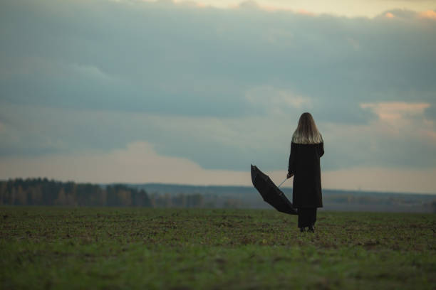 Woman with umbrella on the field.