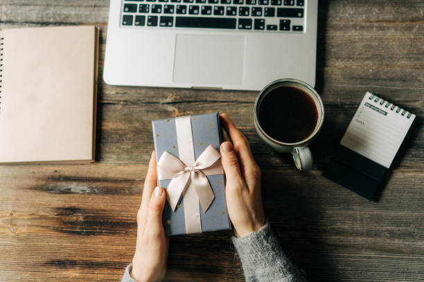 istock Female hands holding a Christmas gift box over a working office desk. 1797001854