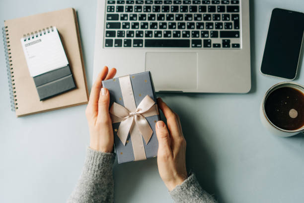 istock Female hands holding a gift box over a working office desk. 1797002377