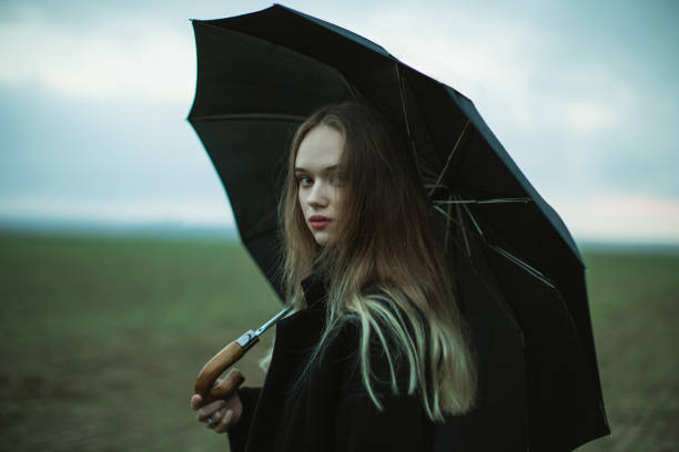 Woman with umbrella on the field.