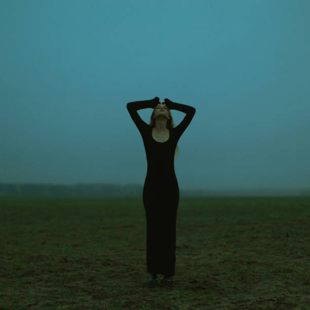 Rear view of blond woman wearing black dress looking at view at the sea with dramatic sky