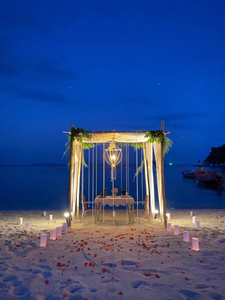 istock Romantic beach setting featuring a scattering of lit candles among a bed of red roses. 1797018954