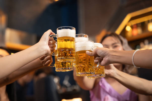 Close-up Group of People Holding Beer and Cheer in Restaurant. Close-up Group of People Holding Beer and Cheer in Restaurant. They Enjoying with Night Party Together. Party, Lifestyle, Happiness, Cheerful and Celebration Concept. glass of bourbon stock pictures, royalty-free photos & images