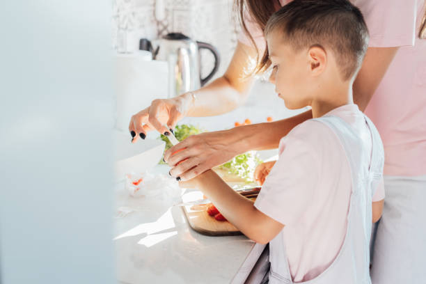 istock Caring young Mother putting a plaster on child finger with wound on from a cut by kitchen knife. First aid in case of small domestic injury. Children's injuries at home. Negligence in cooking at home 1797025828