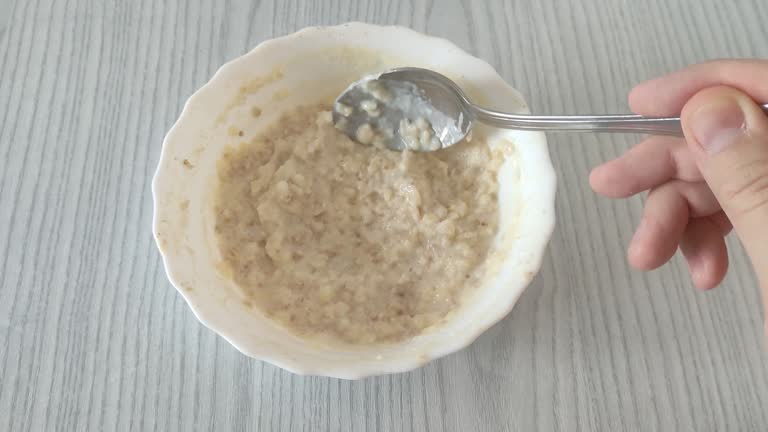 Oatmeal in plate. Man stirs porridge with a spoon