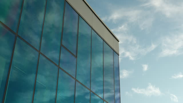 Glass building facade reflecting blue sky and clouds.