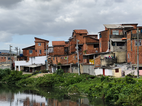 Favela Cidade de Deus in Rio de Janeiro, Brazil. Open sewer, with a lot of pollution and dirt. Wooden and brick houses on the edge. Poverty situation in South America. Shanty town. Slum.