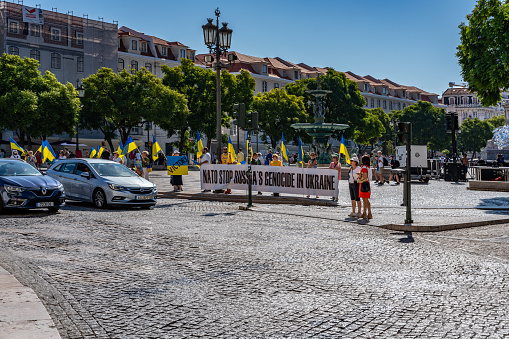 Lisbon, Portugal - Sep 30, 2023: People protest in the square with slogans NATO STOP RUSSIA'S GENOCIDE IN UKRAINE. View of the famous landmark -  Rossio square and Teatro Nacional Dona Maria II,  Lisbon, Portugal.