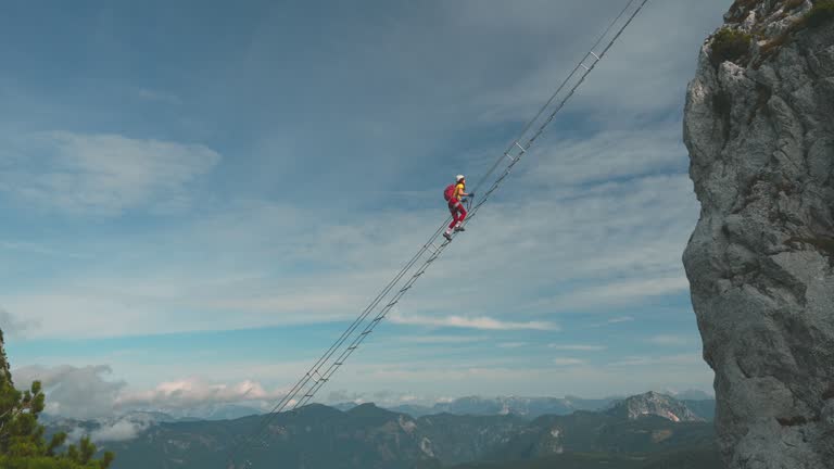 Woman climbing the ladder on via ferrata in Austria