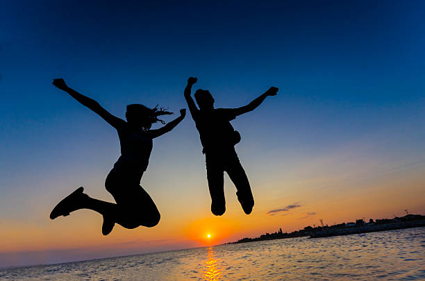istock Joy, Silhouette Beautiful couple are having fun jumping over sunset 179707702