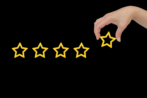 Woman's hand put the stars to complete five stars. Customer satisfaction concept. copy space and the background of the blackboard. giving a five star rating. Service rating, satisfaction concept