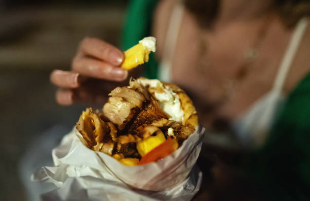 Woman eats pita with meat at night.