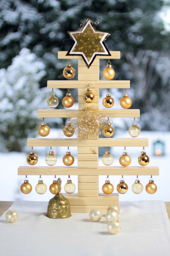 Home-made wooden Christmas tree in front of snow covered terrace