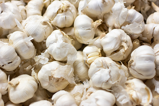 Detail of a pile of white garlic bulbs garlic on display at the market.