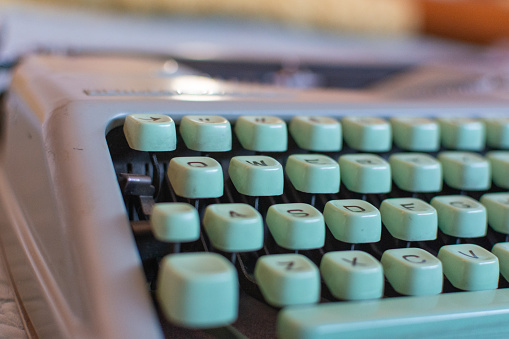 Old-fashioned typewriter sitting on a desk, with copy space on the blank paper and on the background.