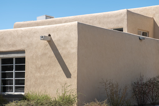 Architectural detail of a southwest style building. Half the building is in direct sunlight and half is shaded.