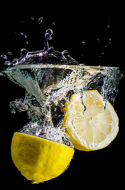 two halved lemons splash into water stock photo