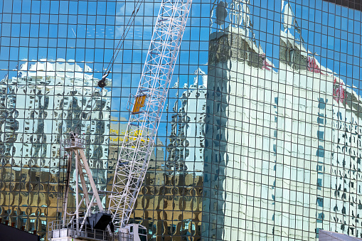 Construction of skyscraper in the city with reflection on glass building behind, background with copy space, full frame horizontal composition, Sydney Australia