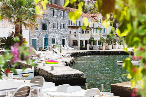 View of beautiful Rose village quayside on Lustica peninsula, Kotor Bay, Montenegro. Beautiful blurred flowers and grapevine frame. Selective focus