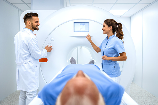 Doctors preparing patient for full body scanning procedure inside MRI diagnostic room.