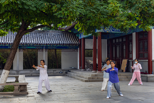 JINAN, CHINA, JUNE 26, 2023: Early morning, people practiced Chinese fight art in a park as part of their fitness routine near the Buddha statue  in Qianfo Shan park  , Jinan, Shandong Province, China